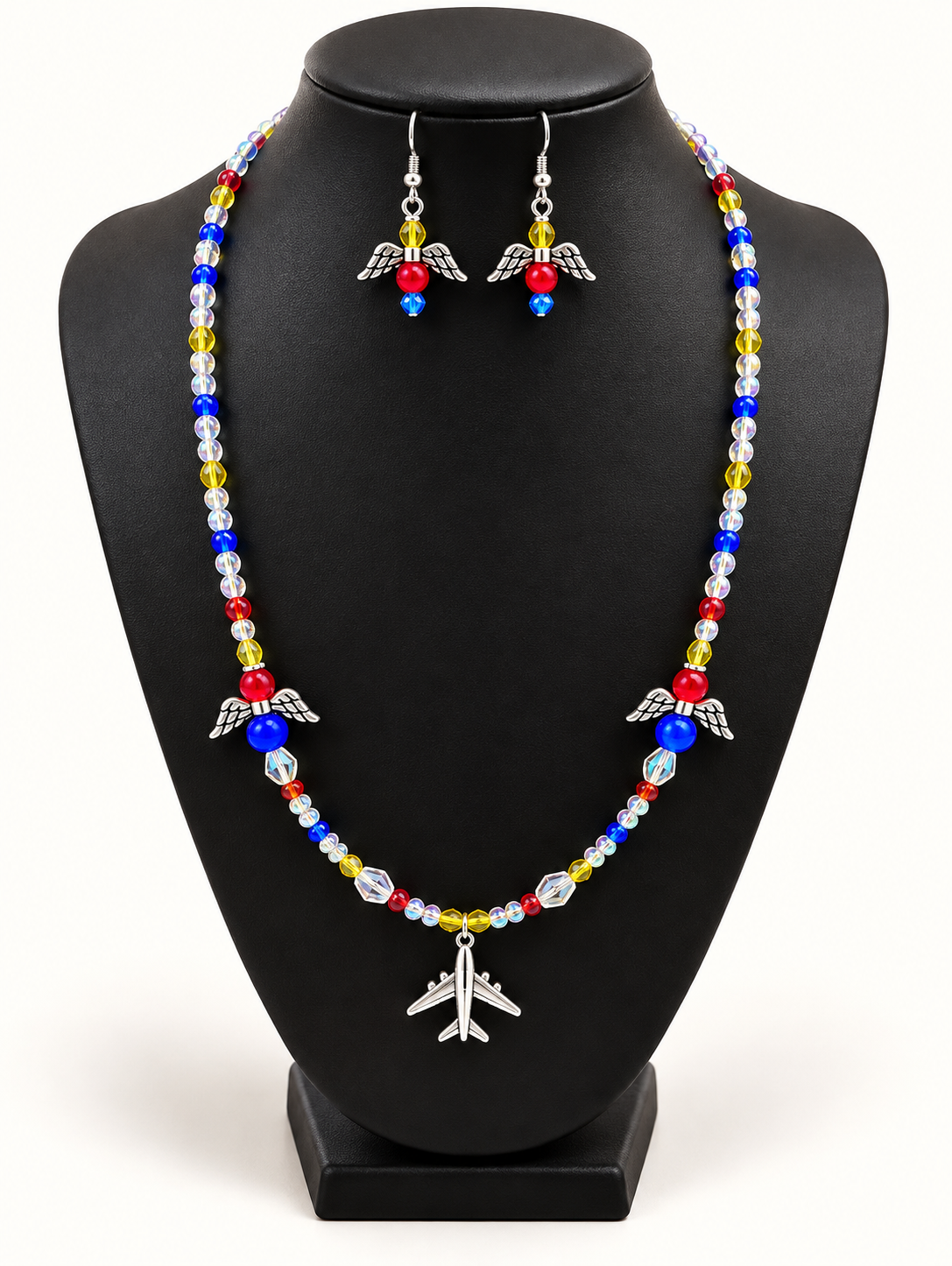 Beaded necklace with angel-wing charms and airplane pendant on a black bust