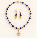 Cobalt-blue beaded necklace with yellow, red, and iridescent accents and a gold-tone airplane pendant, with matching gold-tone drop earrings