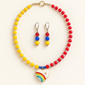 Yellow and red color-block beaded necklace with iridescent spacers, gold-tone clasp, and enamel rainbow heart pendant, with matching gold-tone drop earrings